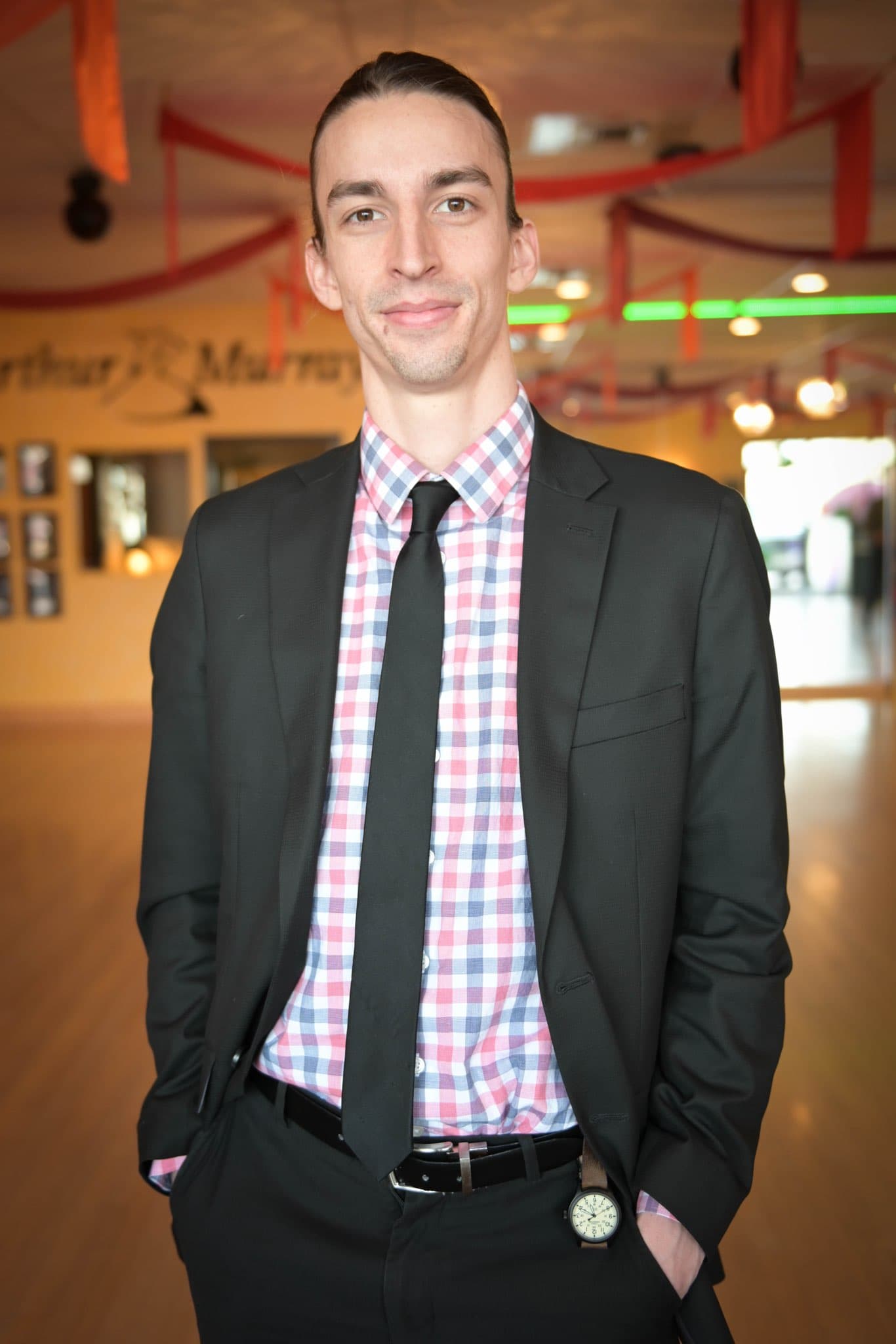 A headshot of Zach wearing a suit with a blue and red shirt.